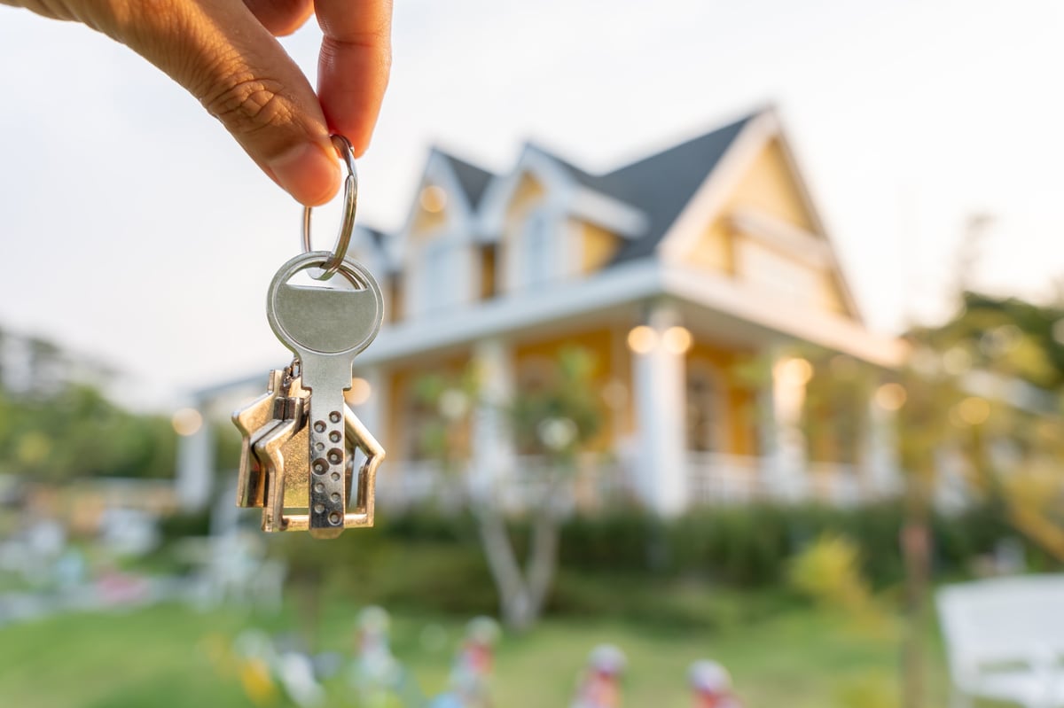 A smiling real estate agent holding keys for a new owner